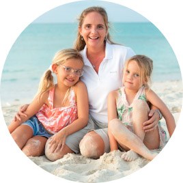 A woman and two young girls sitting together on a Turks and Caicos beach