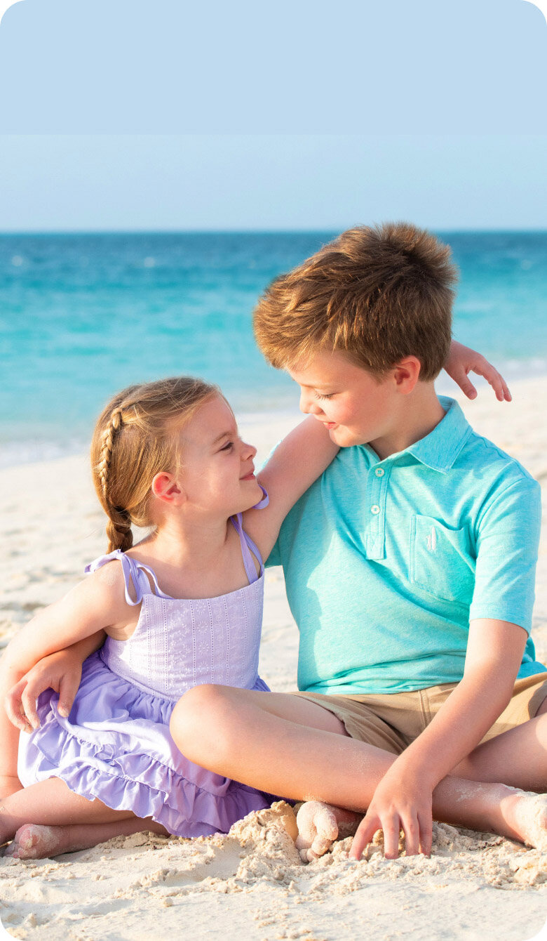 Brother and sister sitting together on the beach