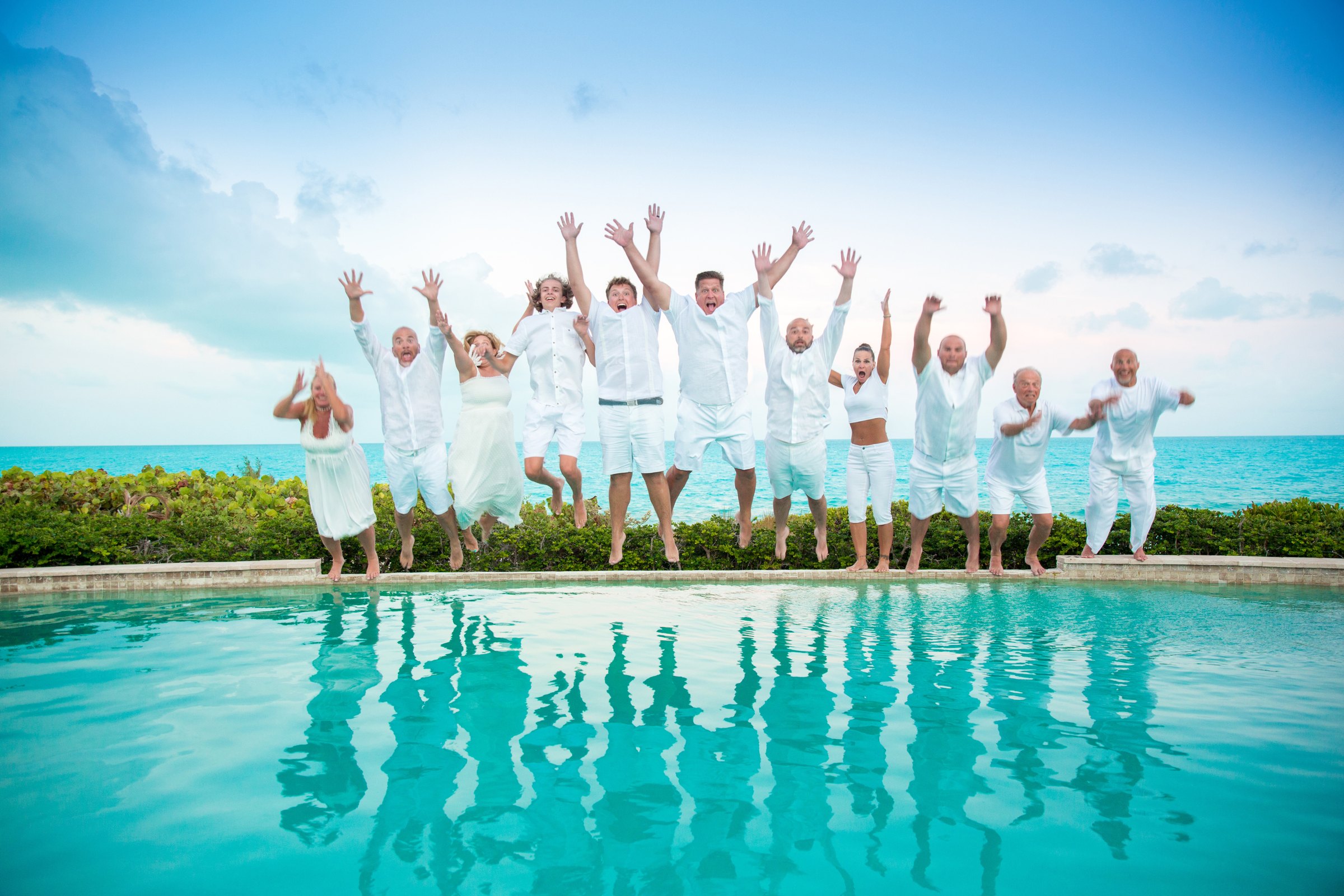 A group celebrating with a poolside jump in Turks & Caicos