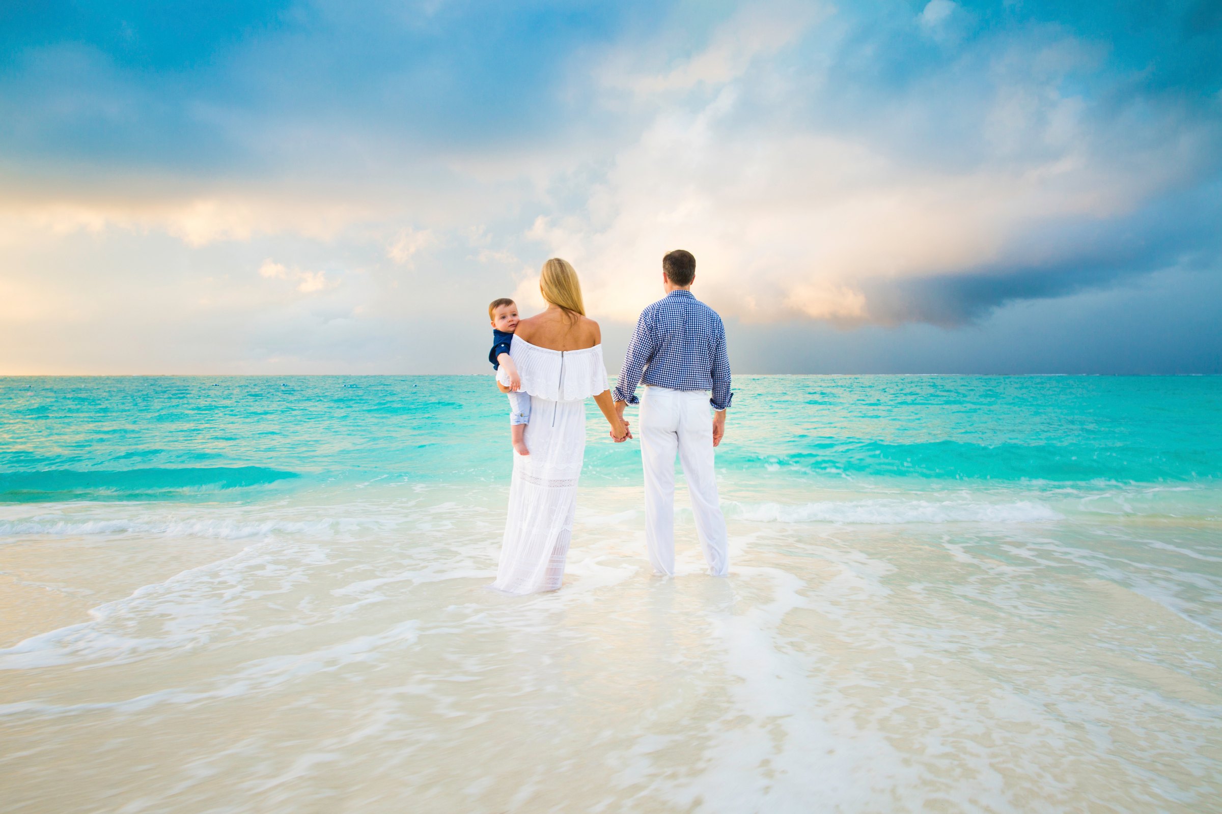 A family standing together in the turquoise shallows of Turks & Caicos