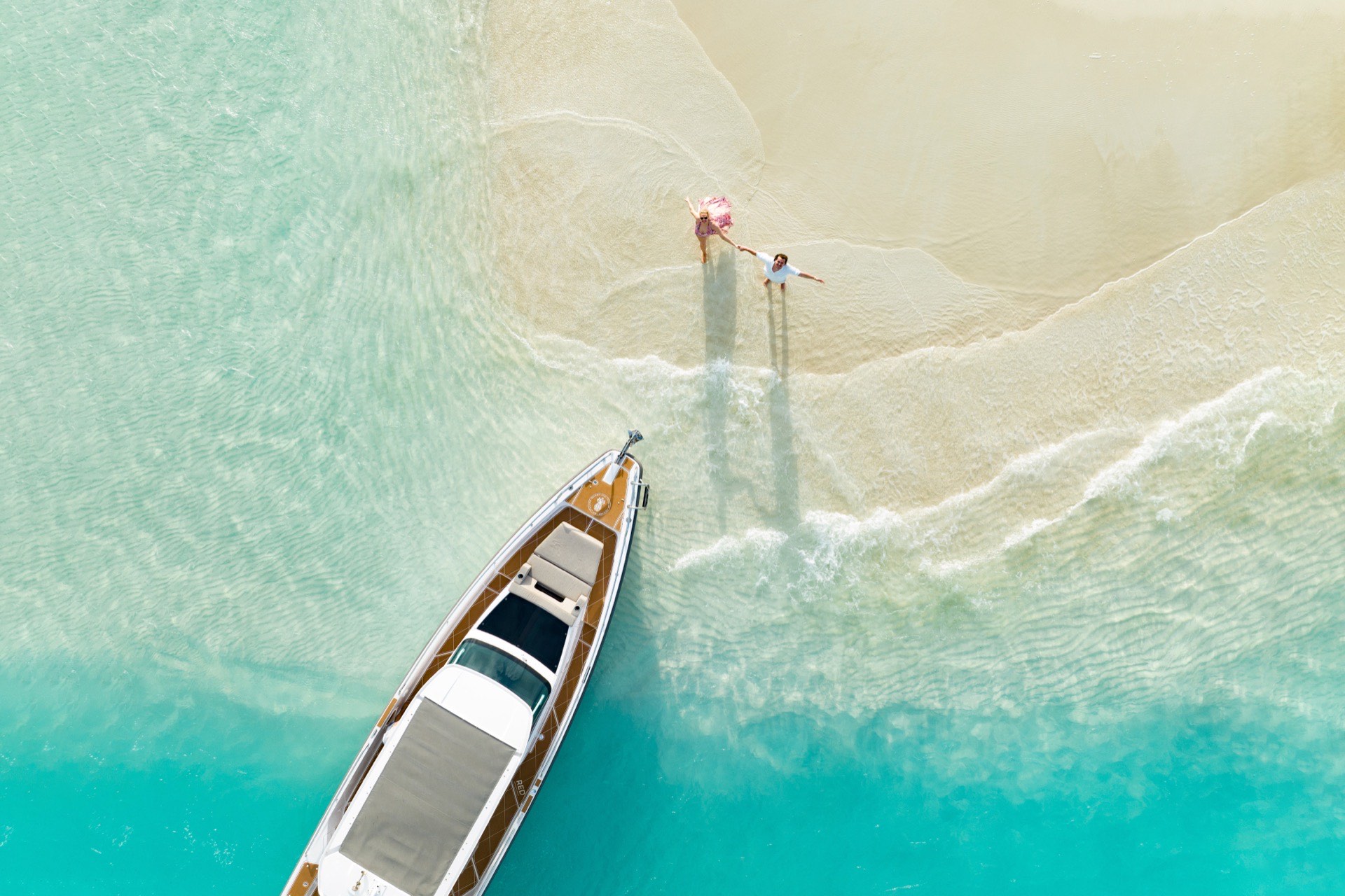 Aerial view of a couple on a Turks & Caicos sandbar beside a boat
