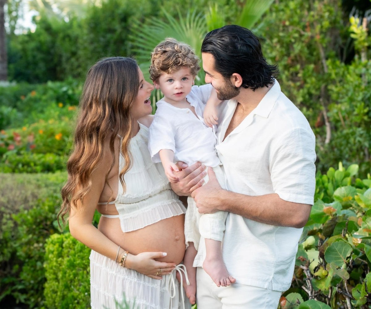 Parents holding their toddler in a tropical garden