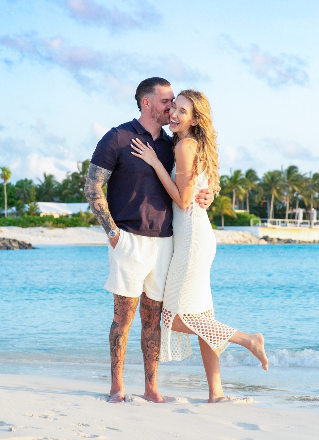 Tattooed groom kissing his bride's cheek on a Turks and Caicos beach