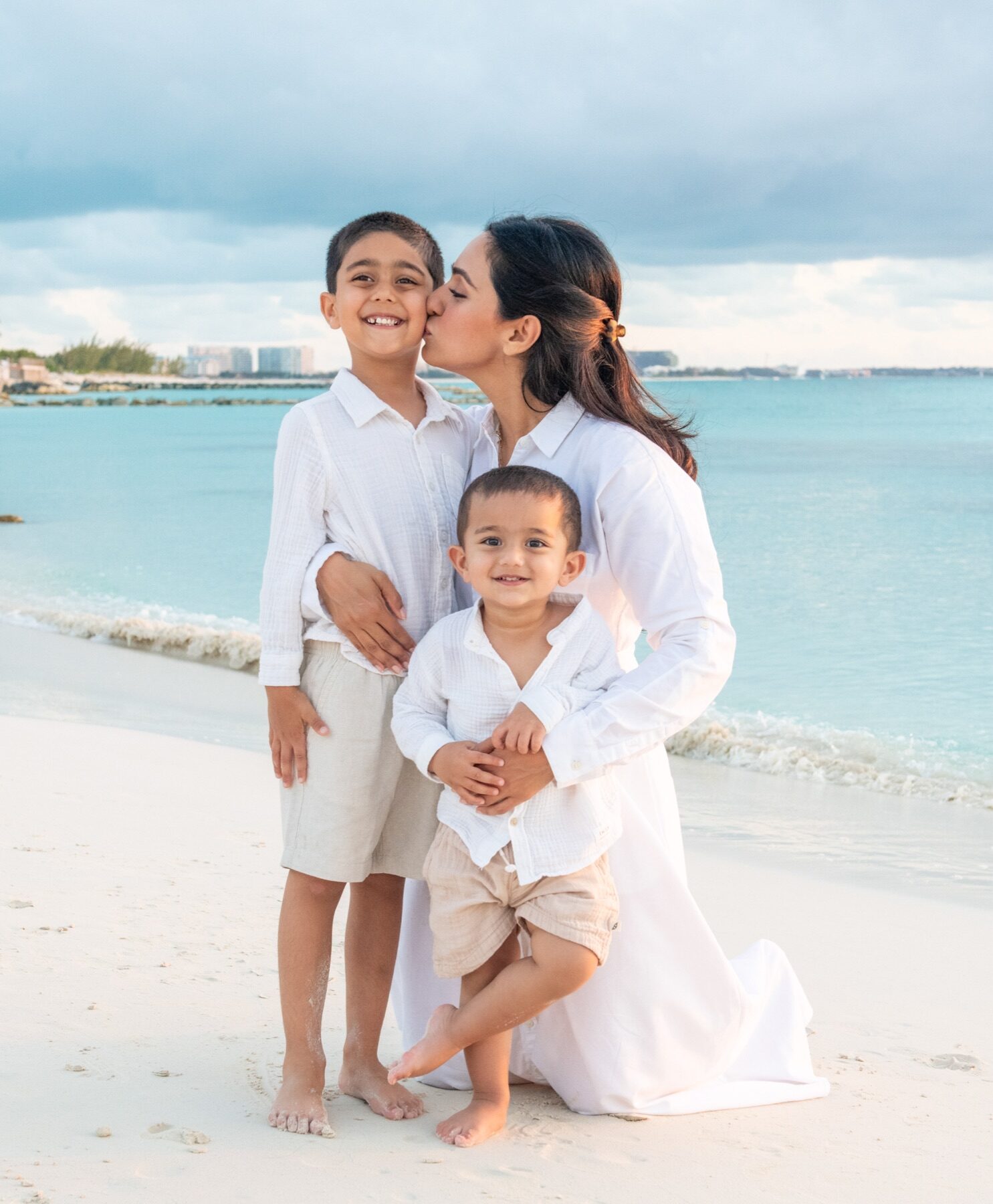 Mother kissing her older son's cheek while holding her younger son, Turks and Caicos