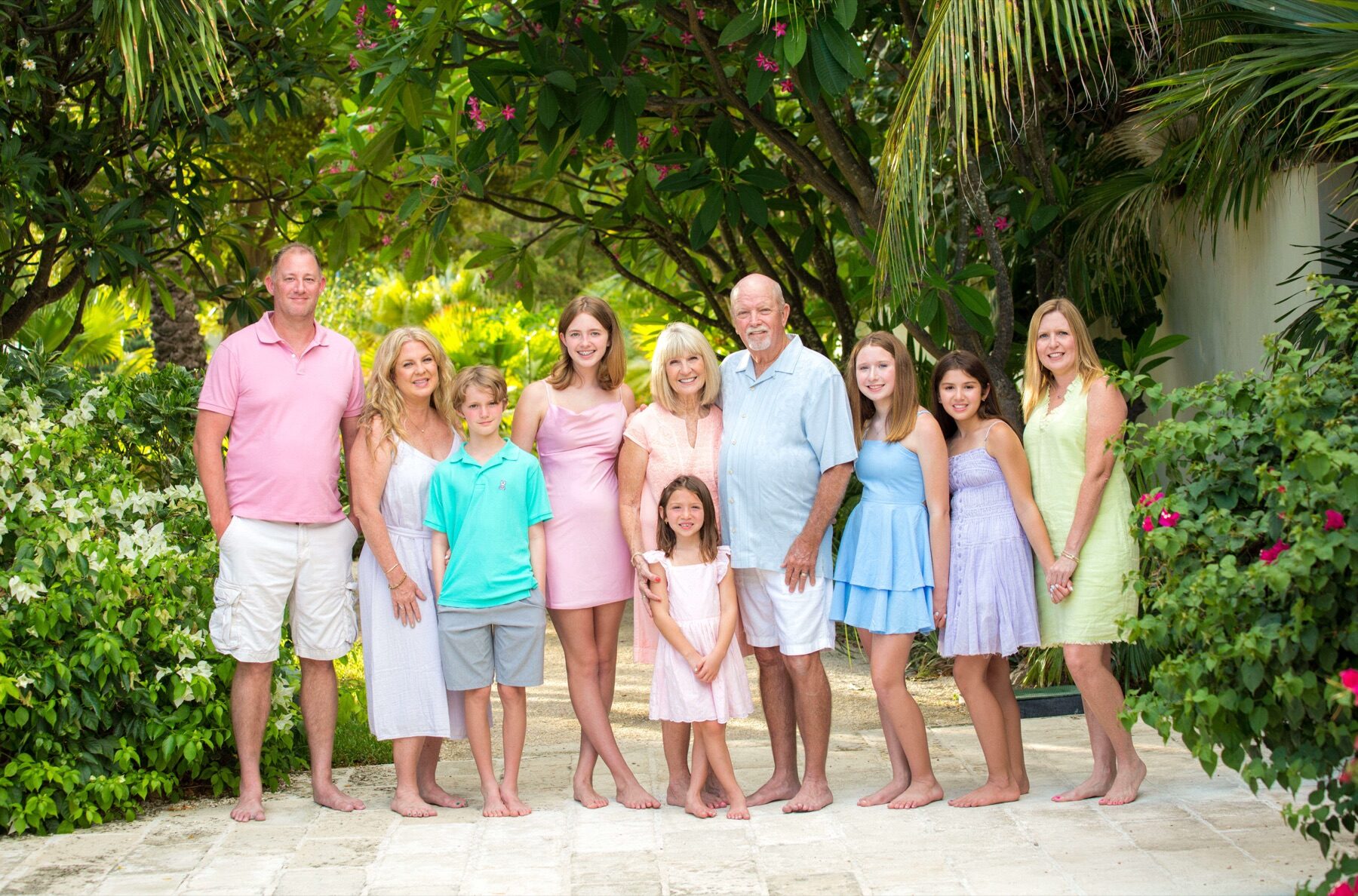 Multigenerational family of ten standing together under a flowering archway
