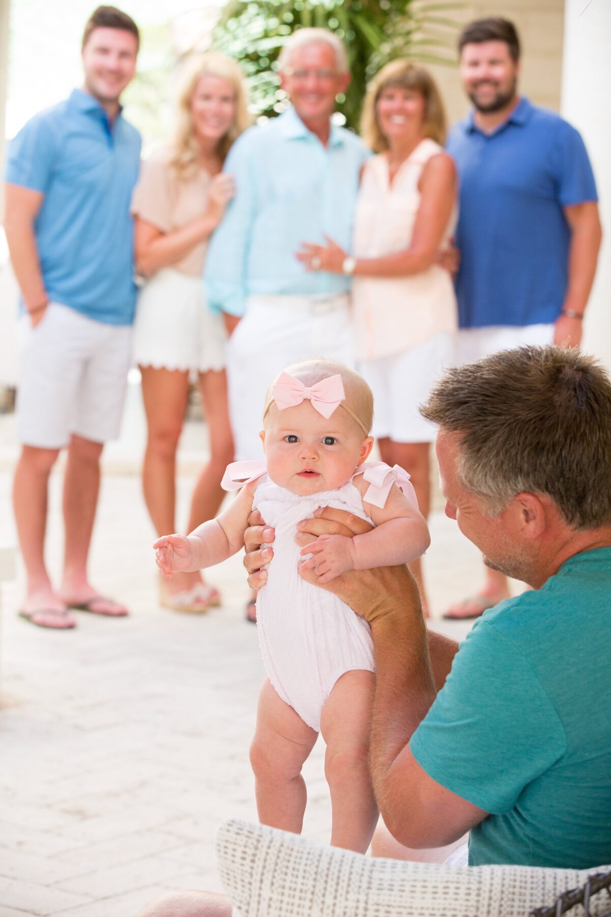 Grandfather holding a baby while relatives look on from a Turks and Caicos porch