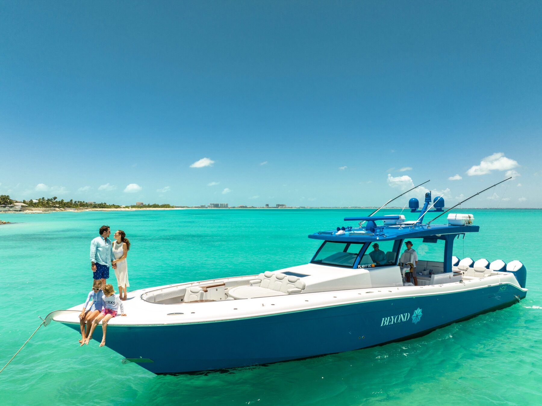 Family standing on the bow of a sport fishing yacht anchored near shore