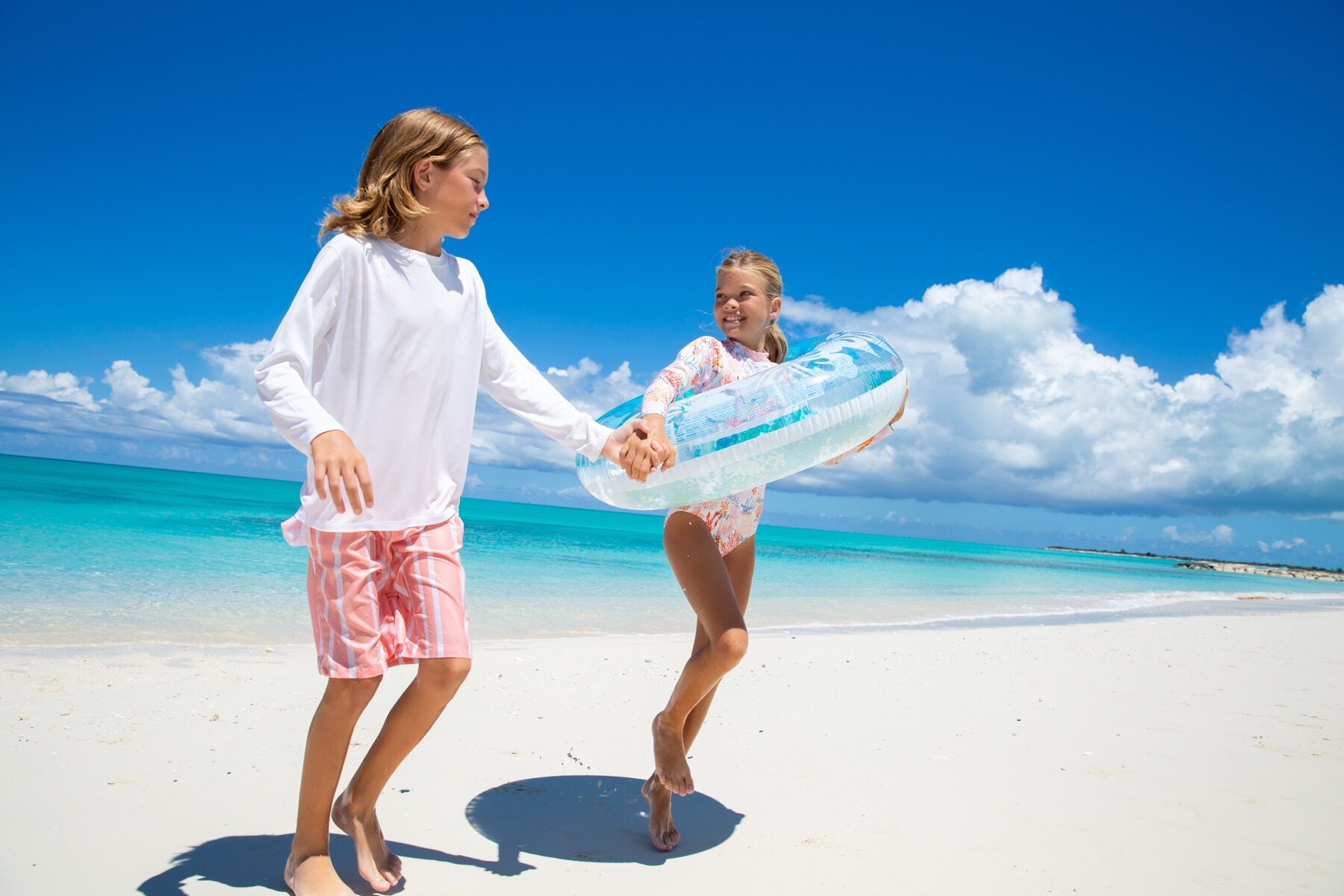 Two children playing tug of war with an inflatable ring on the beach