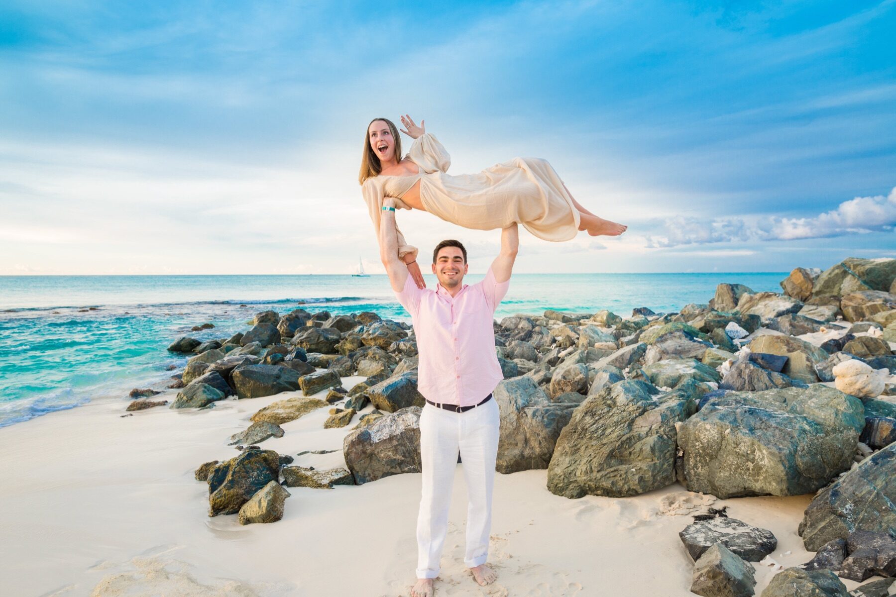Man lifting his cheering partner overhead on rocks in Turks and Caicos