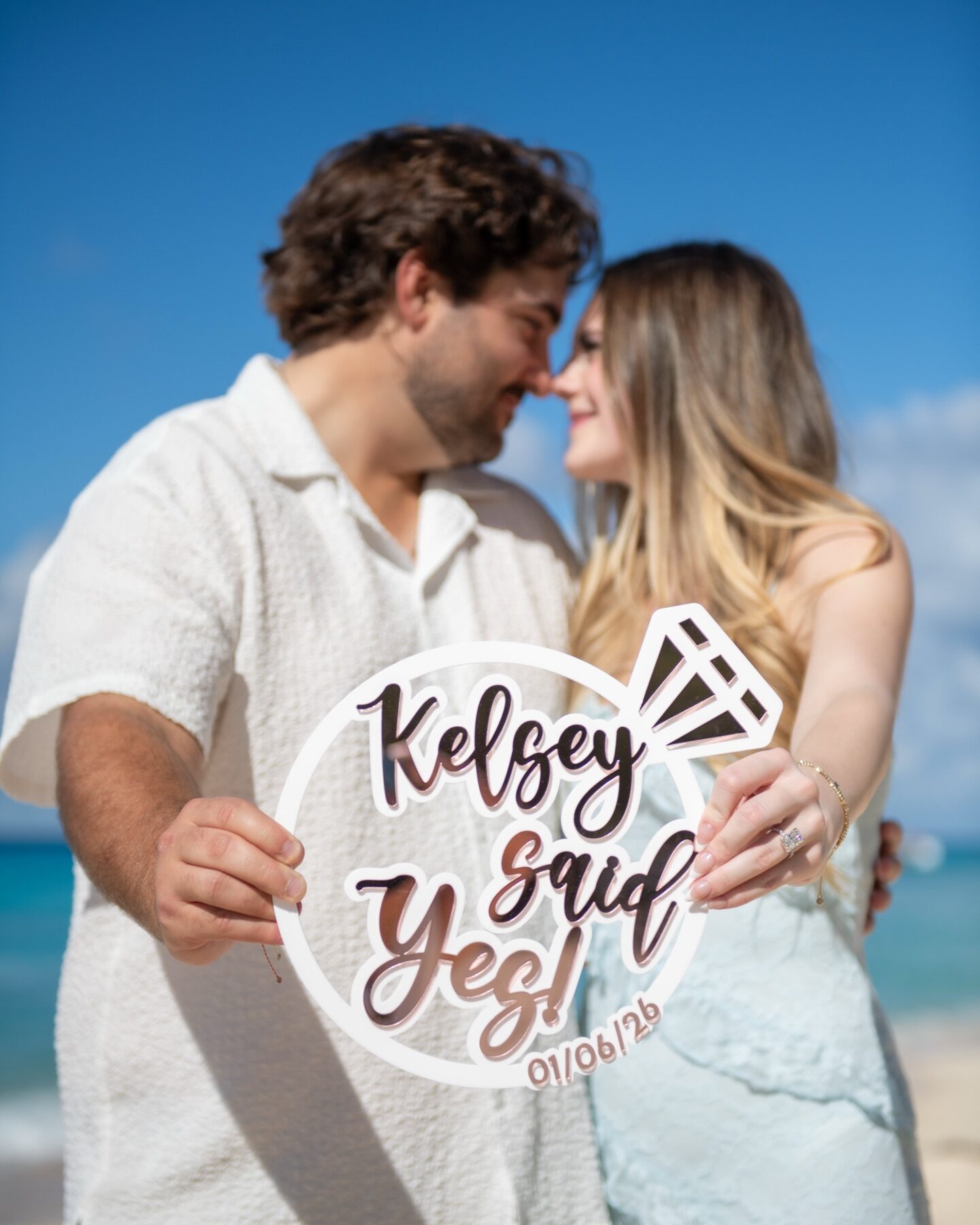 Newly engaged couple nose to nose holding a said yes photo prop