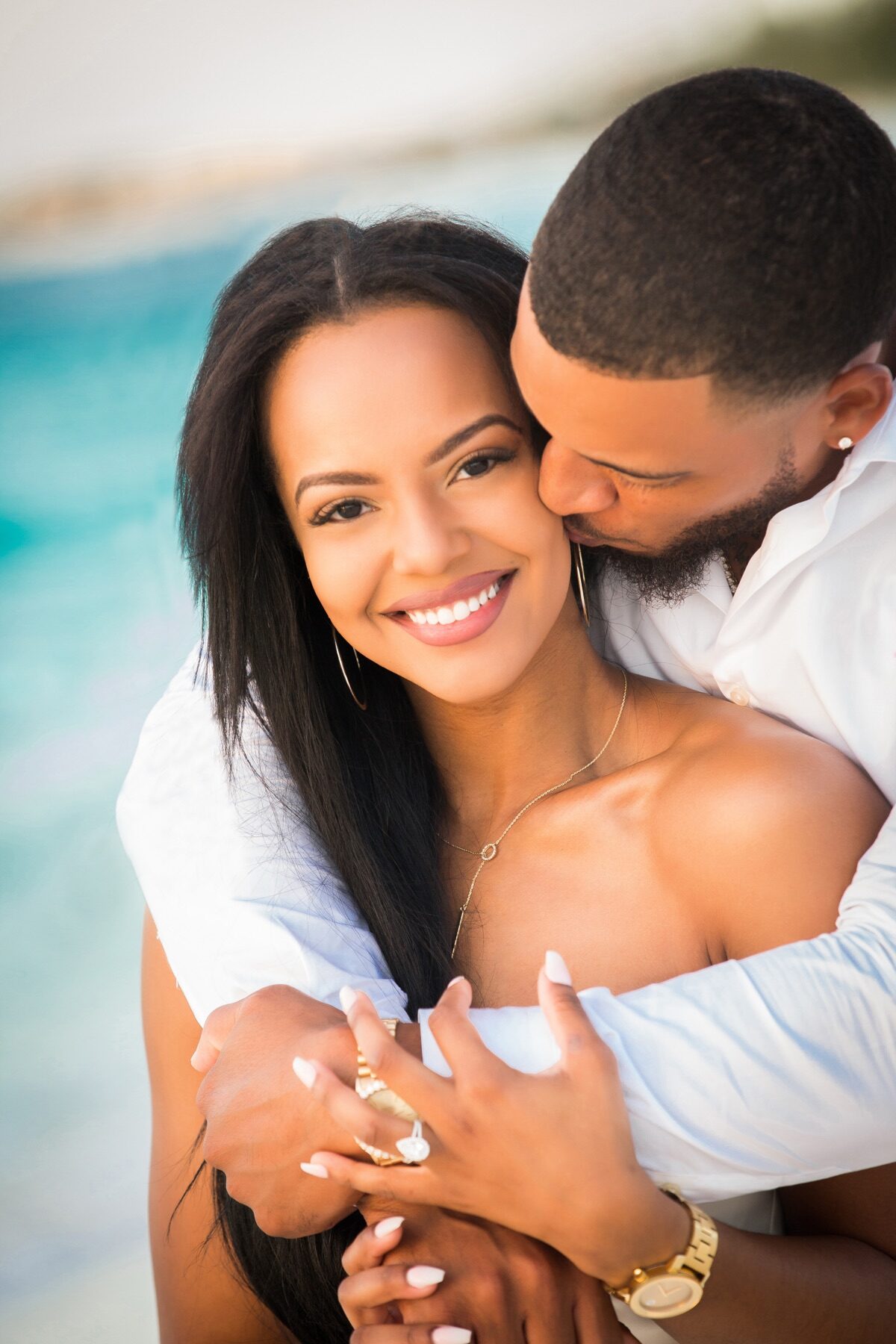 Man kissing his fiancee's cheek poolside at a Turks and Caicos resort