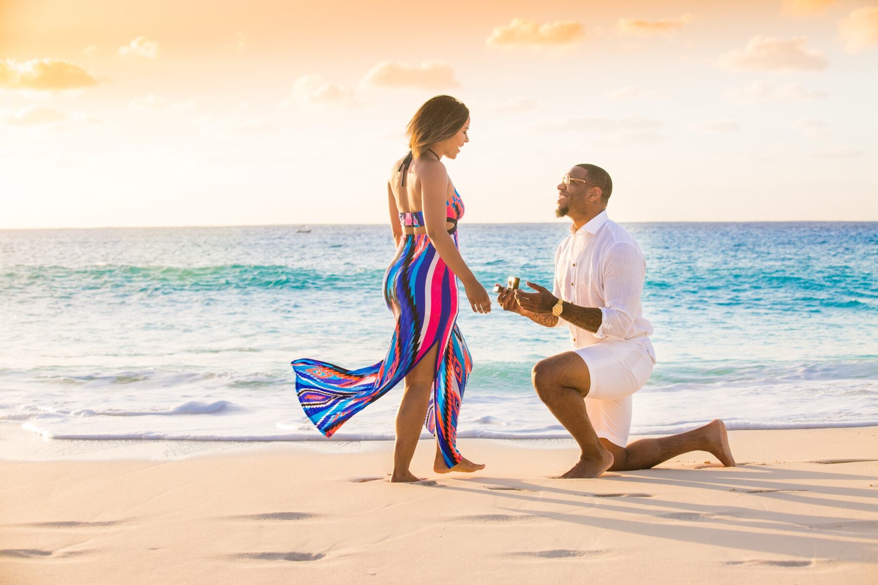Man proposing on one knee to a woman in a striped dress, Turks and Caicos