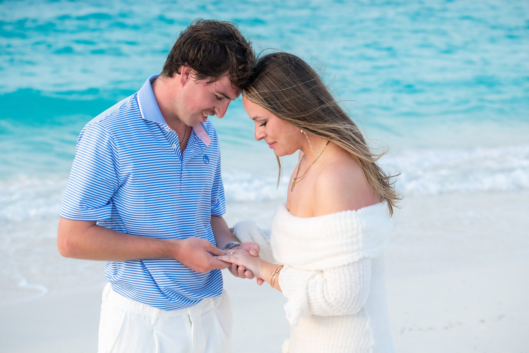 Man placing a ring on his fiancee's finger by the shore in Turks and Caicos