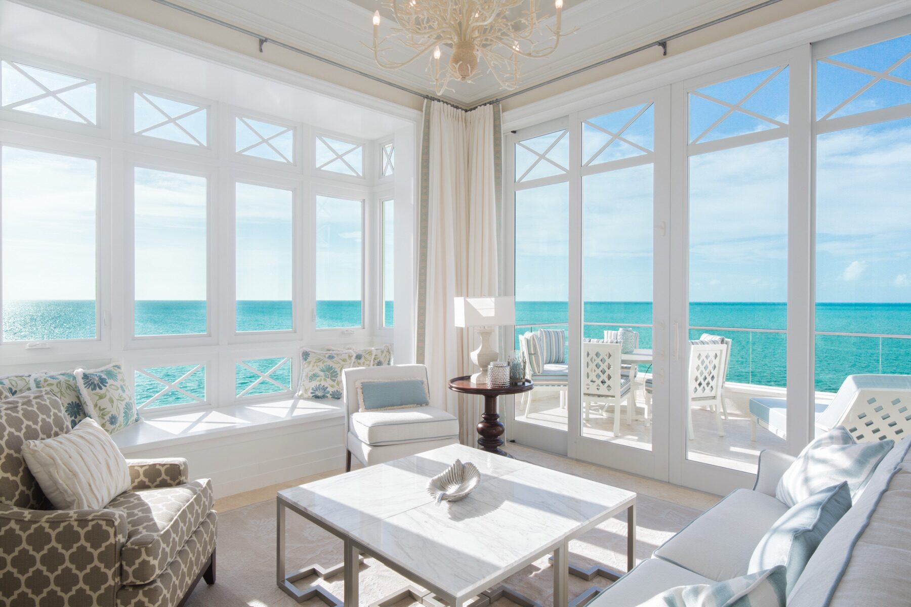 Bright sunroom with white framed windows overlooking the turquoise ocean
