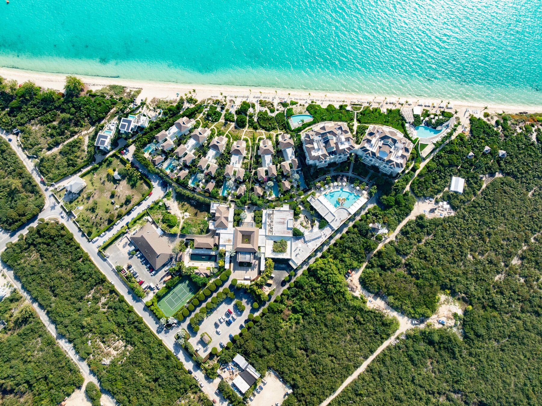 Aerial view of a resort compound nestled between beach and dense greenery