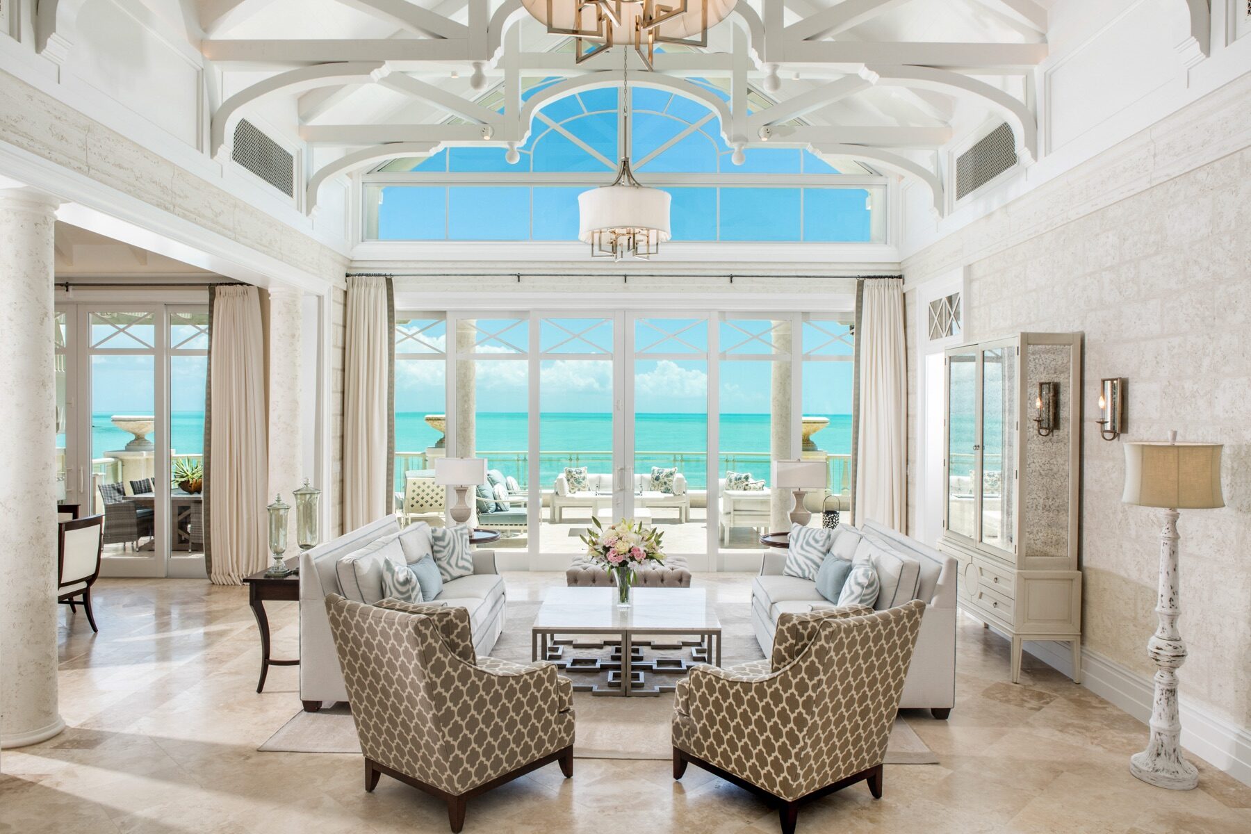 Vaulted living room with arched windows and a chandelier overlooking the ocean