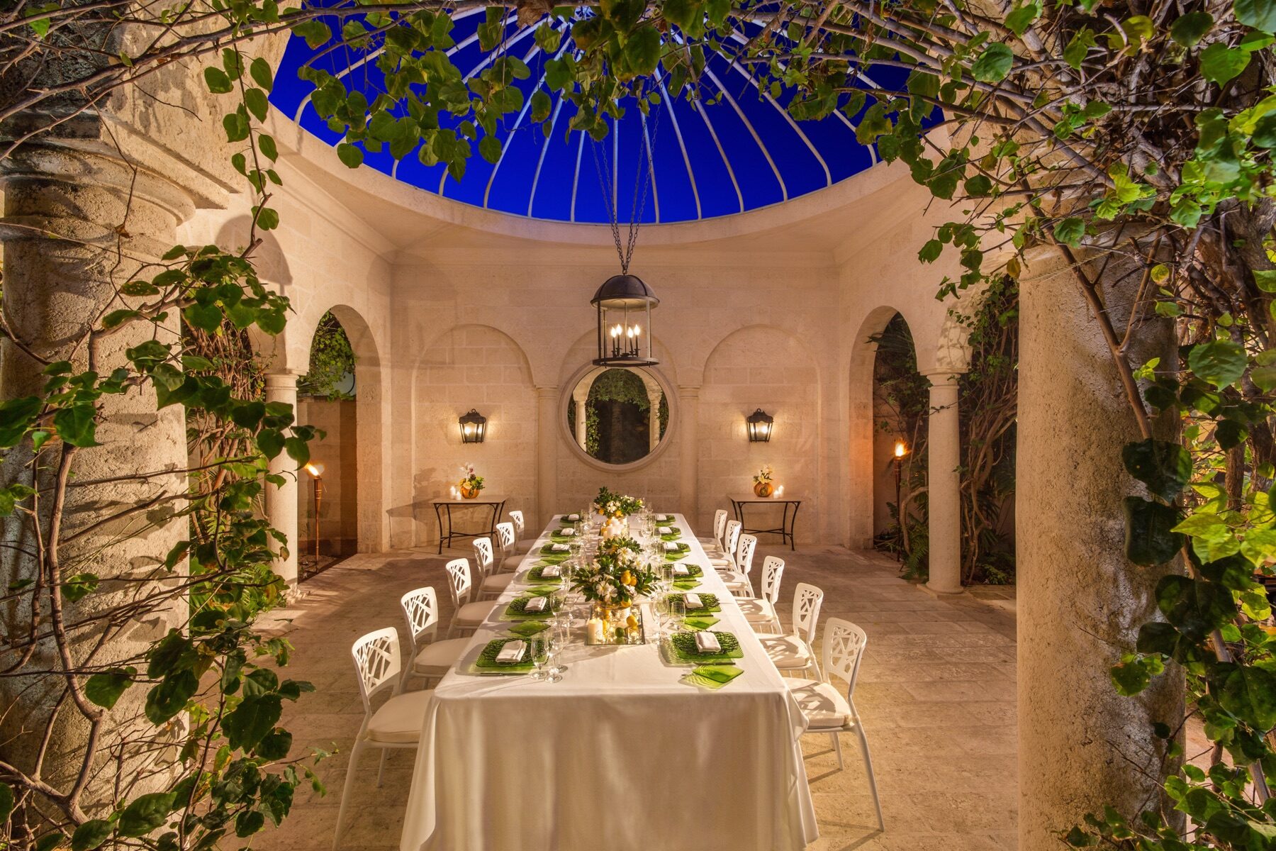 Domed stone dining pavilion set for an evening banquet under climbing vines