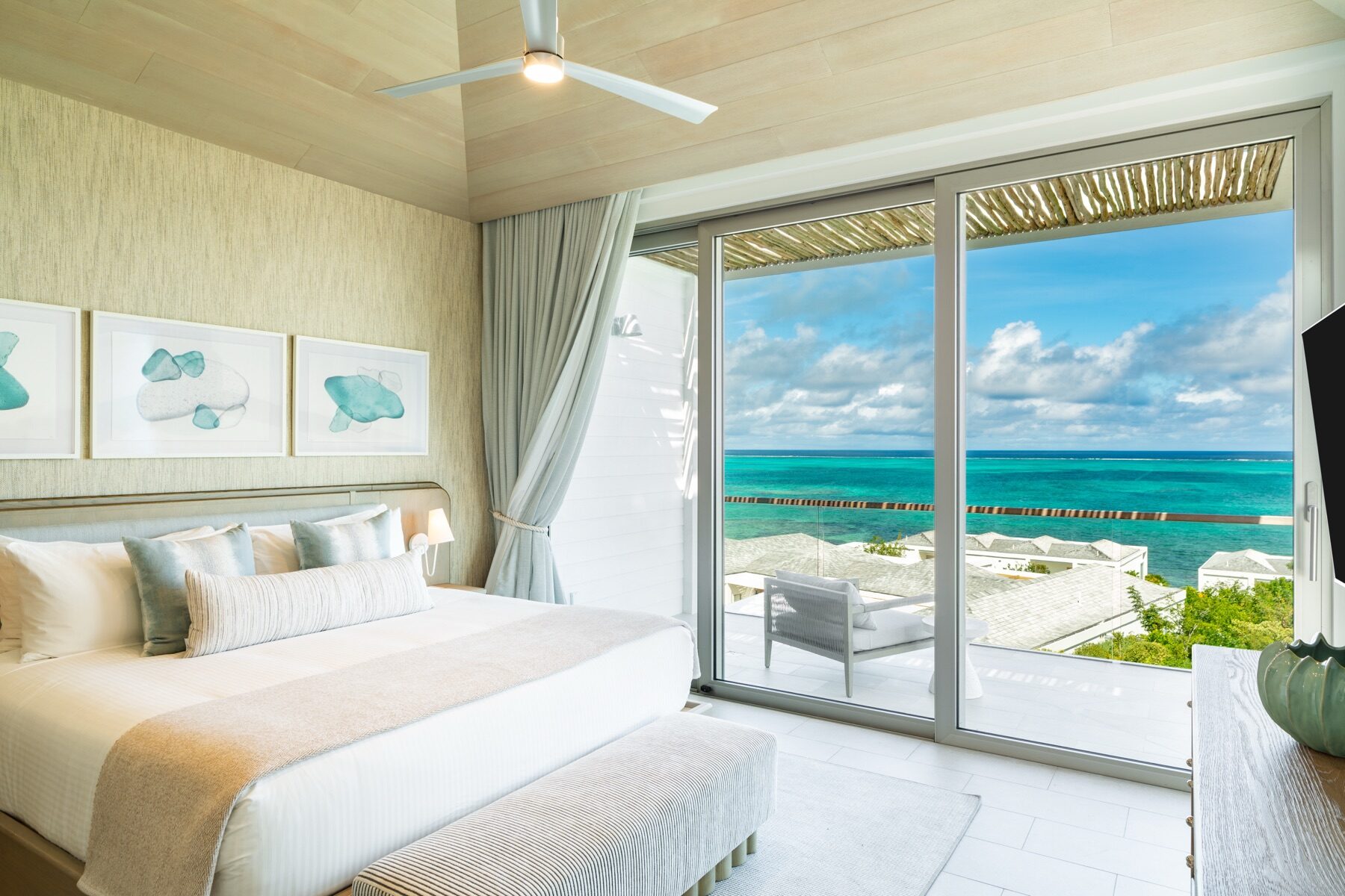 Bedroom suite with a ceiling fan and sliding doors opening to the ocean