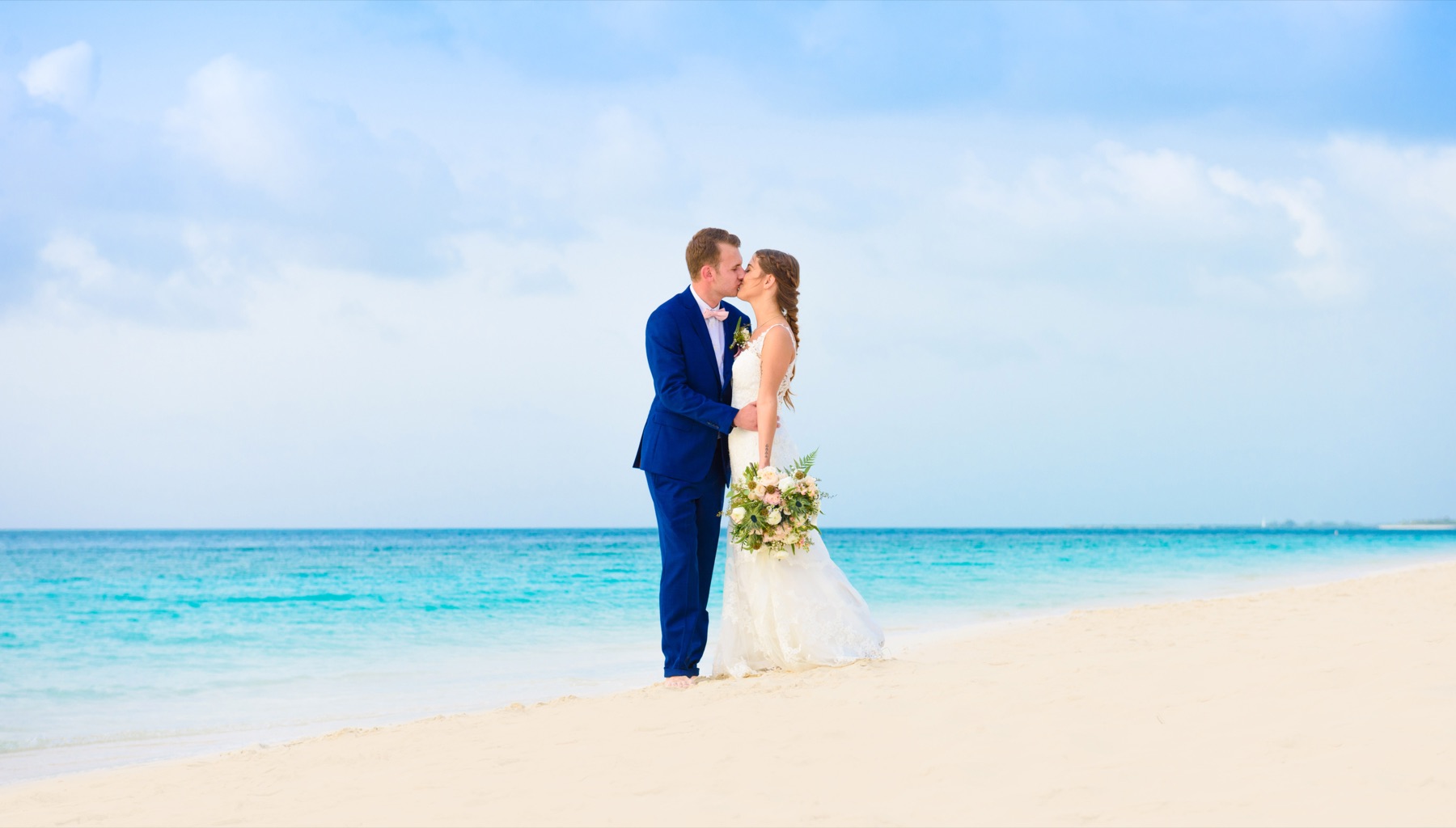 Bride and groom kissing on an empty white sand beach in Turks and Caicos