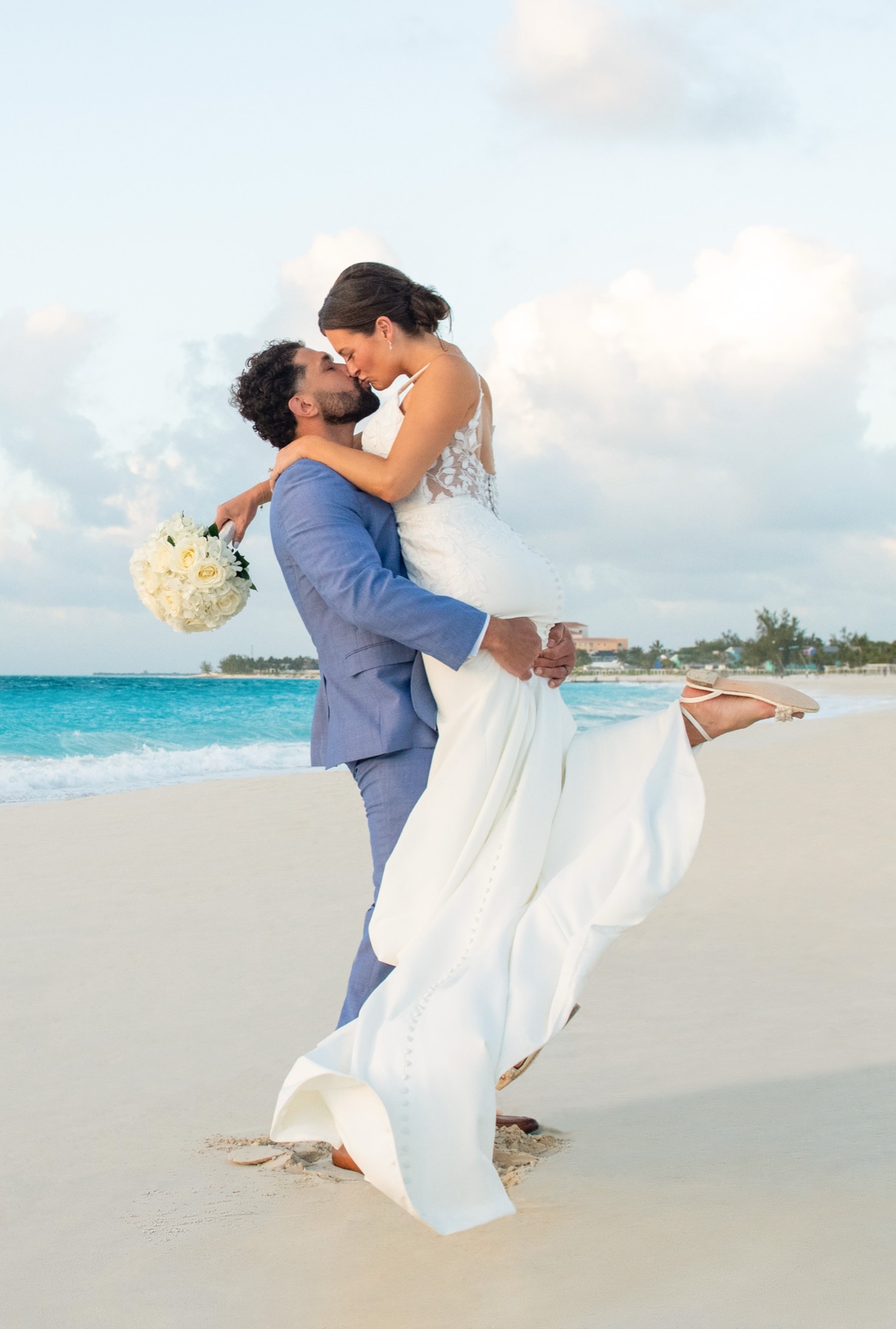 Groom lifting bride off her feet for a barefoot kiss on a Turks and Caicos beach