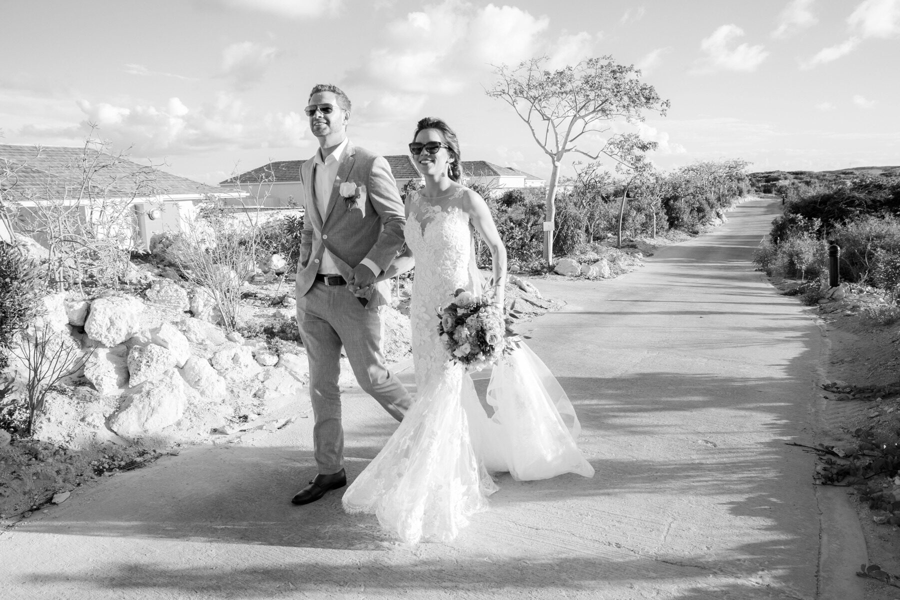 Black and white portrait of bride and groom walking a Turks and Caicos coastal road