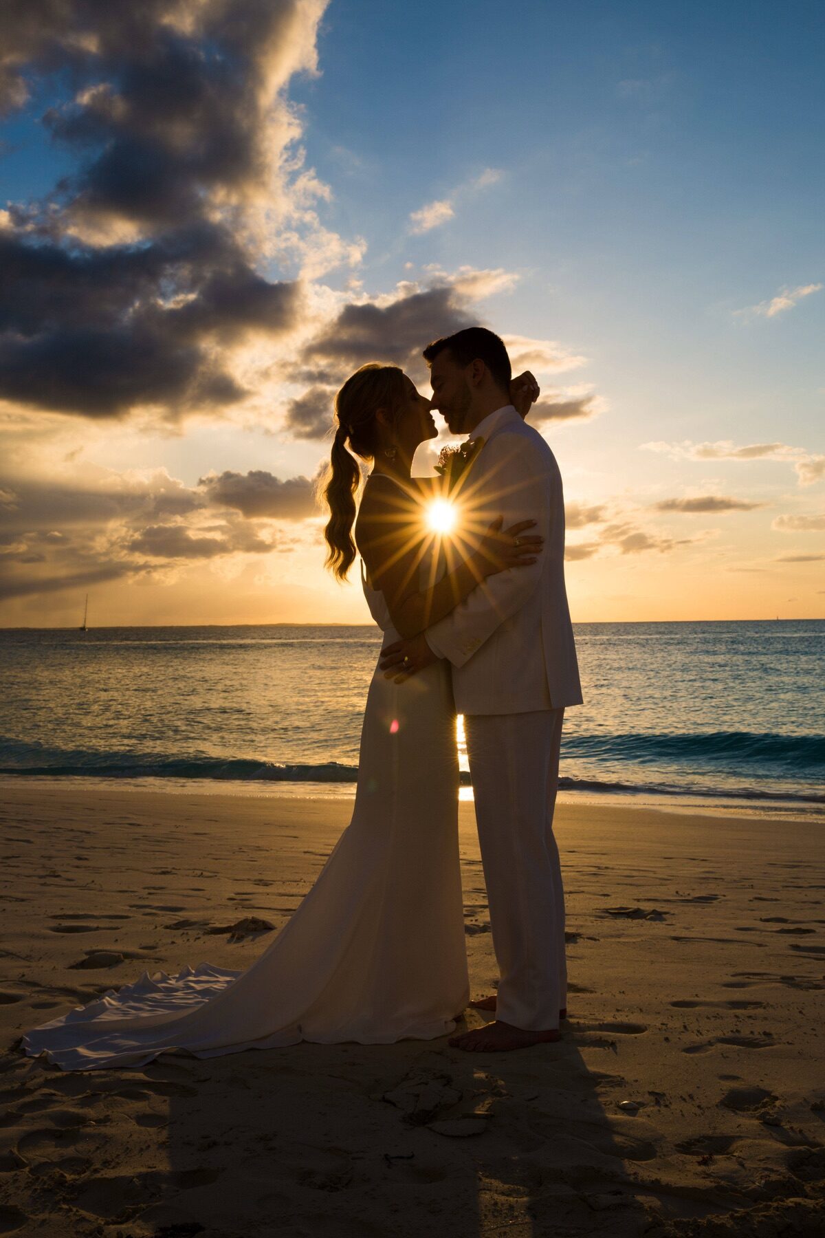 Close silhouette of bride and groom kissing with the setting sun glowing between them