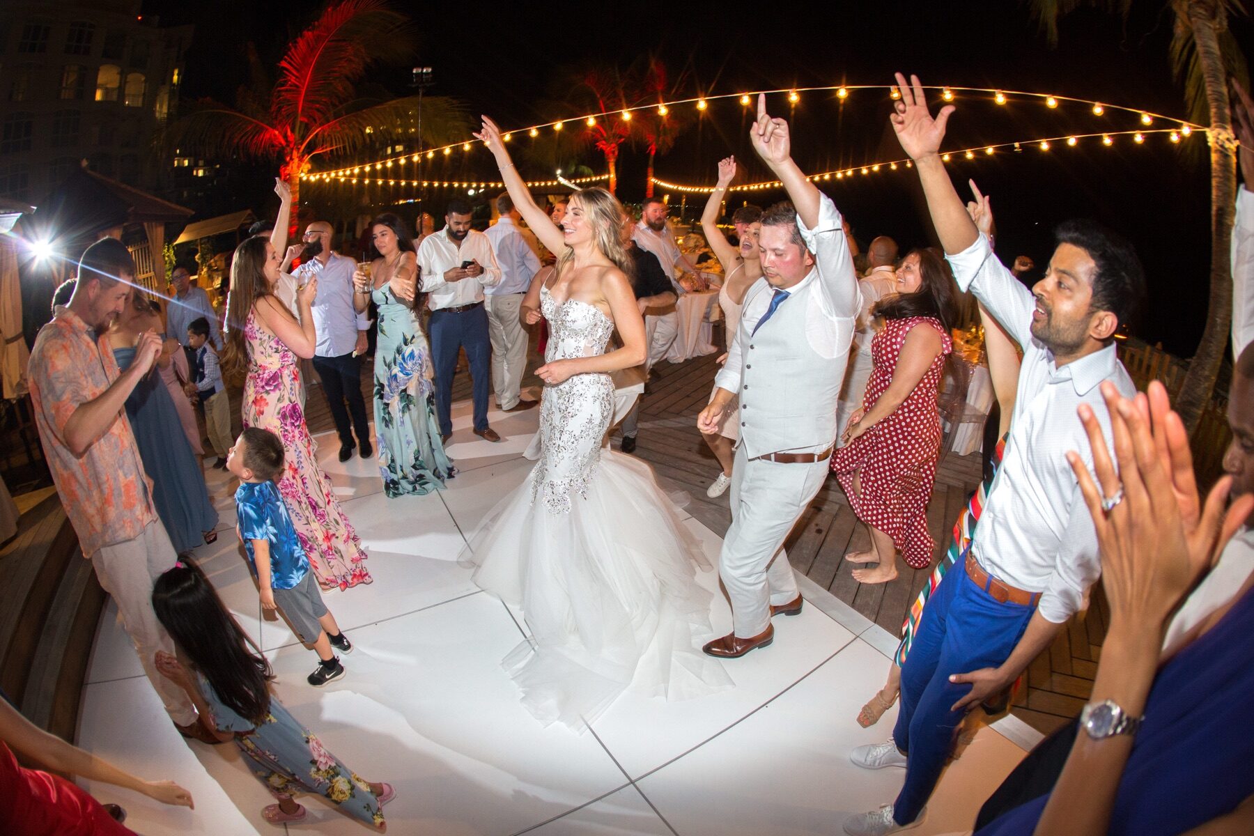Bride dancing with guests under string lights on a Turks and Caicos dance floor