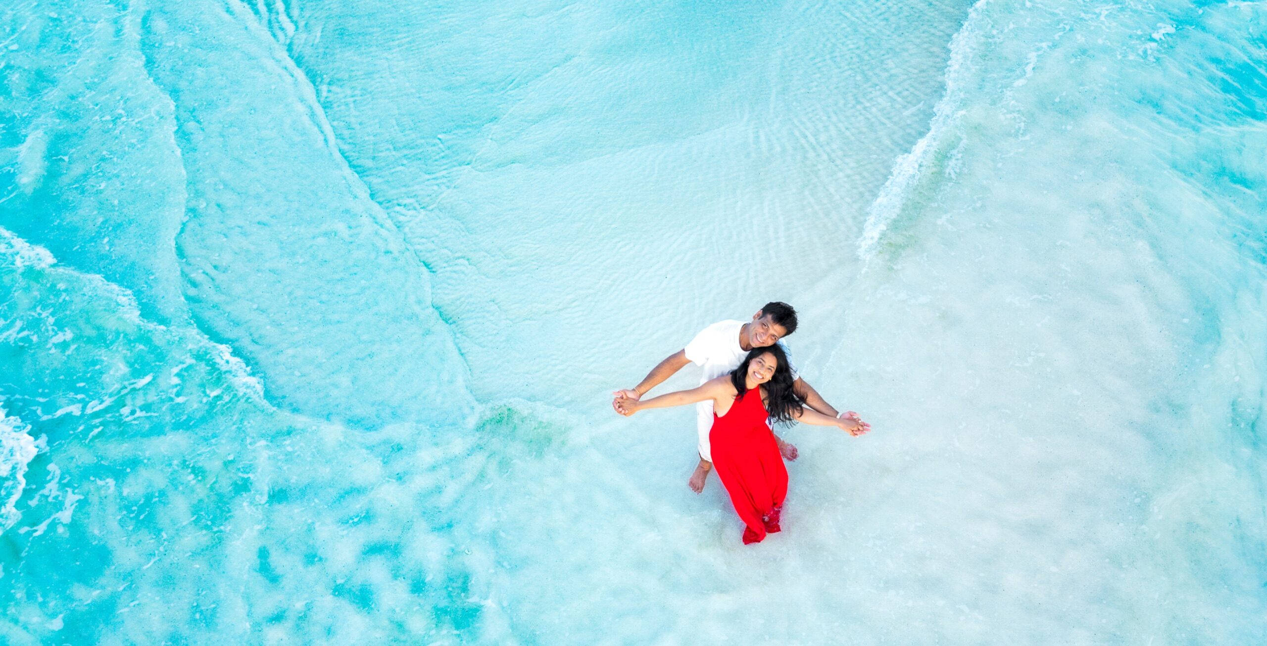 Aerial view of a couple embracing in shallow turquoise water in Turks and Caicos