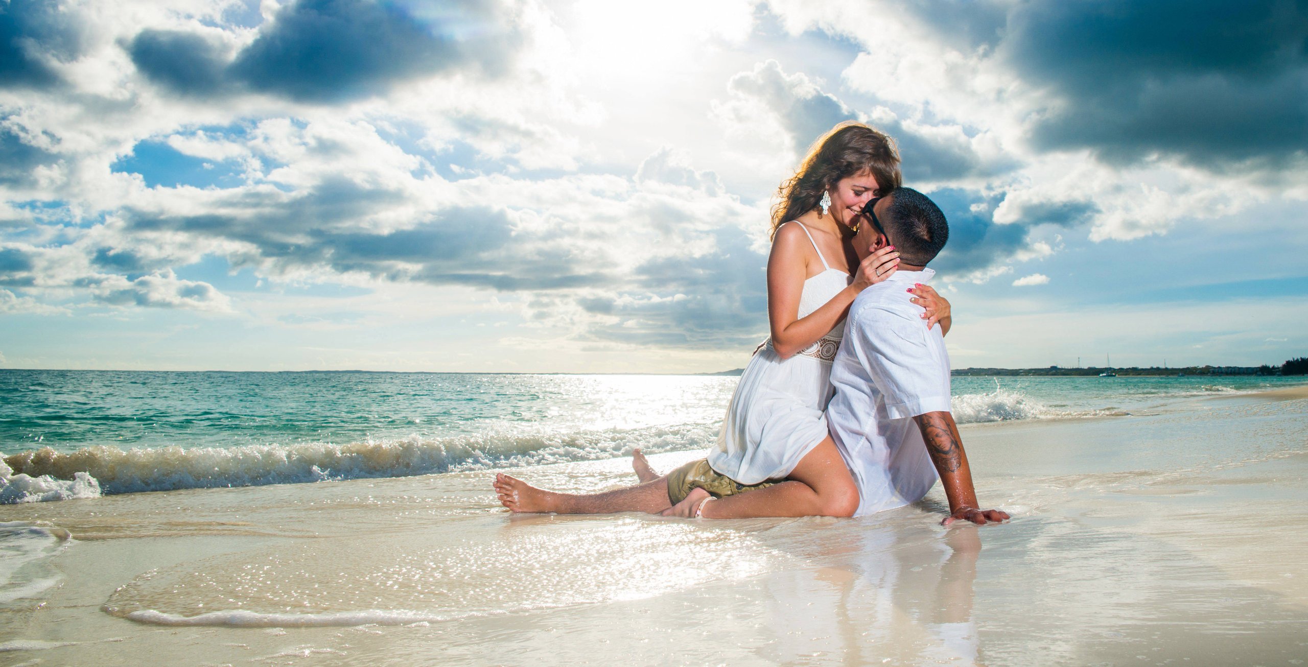 Couple embracing on the beach as the sun sets over the ocean