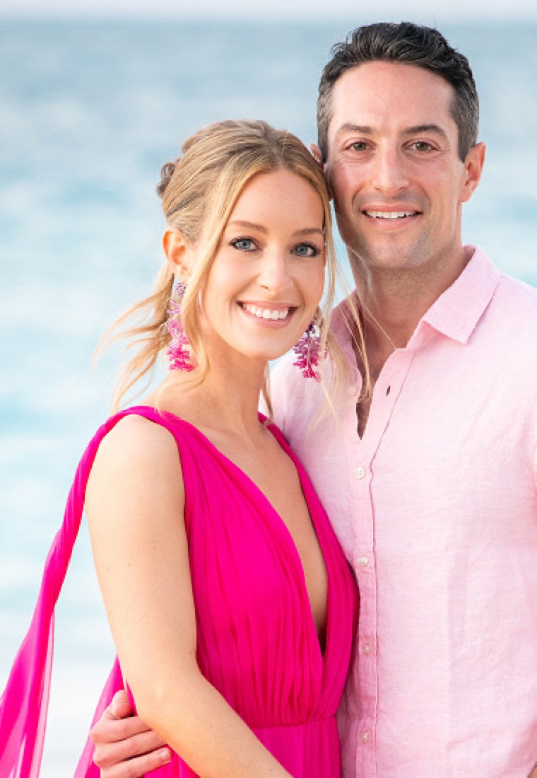Smiling couple on the beach, she in a bright pink dress