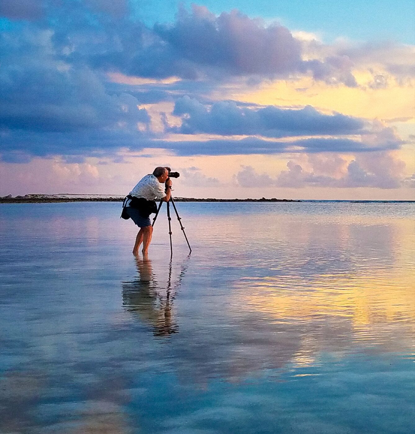 Photographer with tripod in the shallows at sunset, Grand Turk
