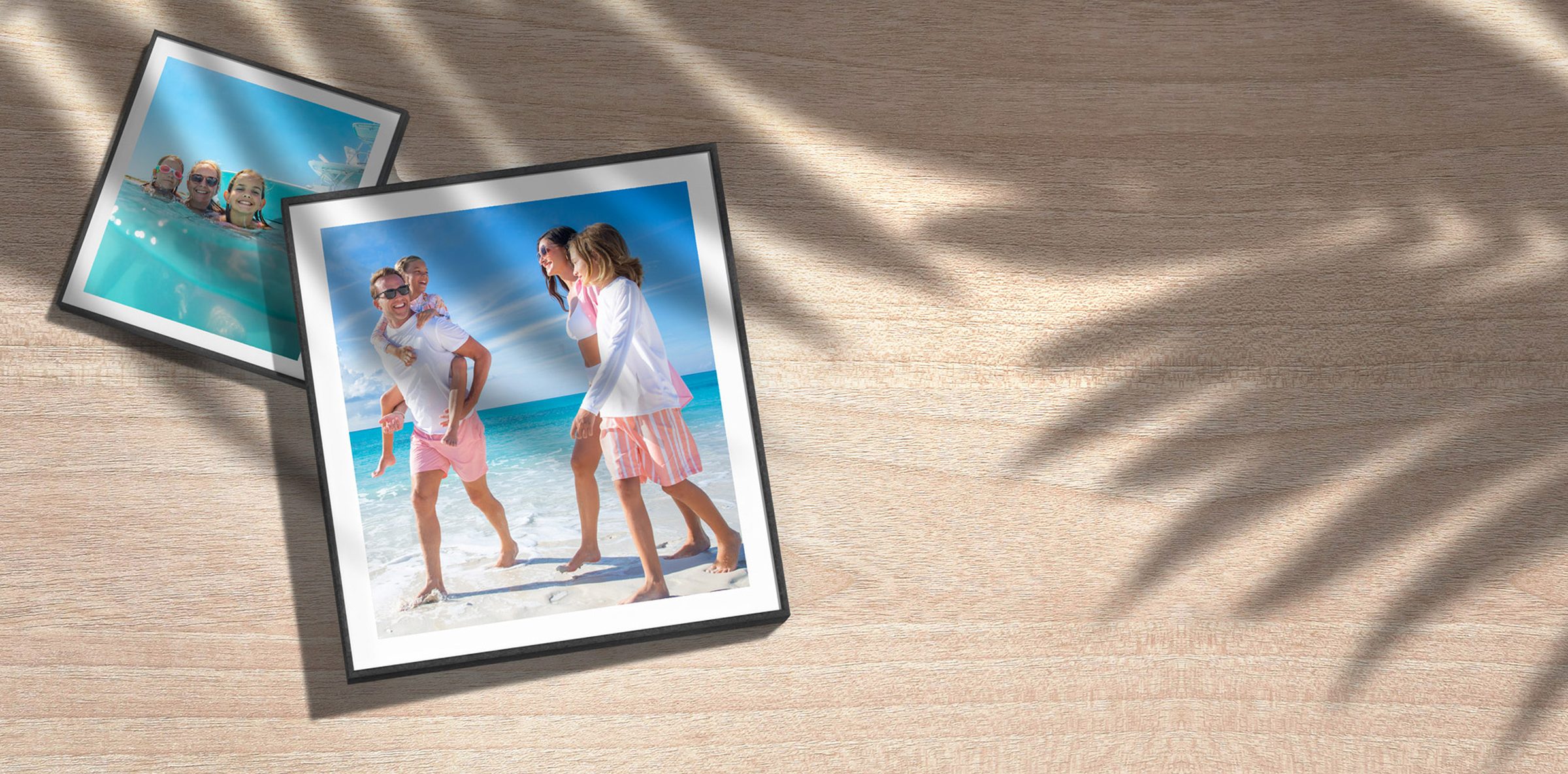 Printed family photos on a wooden table under palm shadows