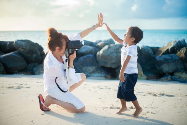 Photographer high-fiving a young boy on the beach