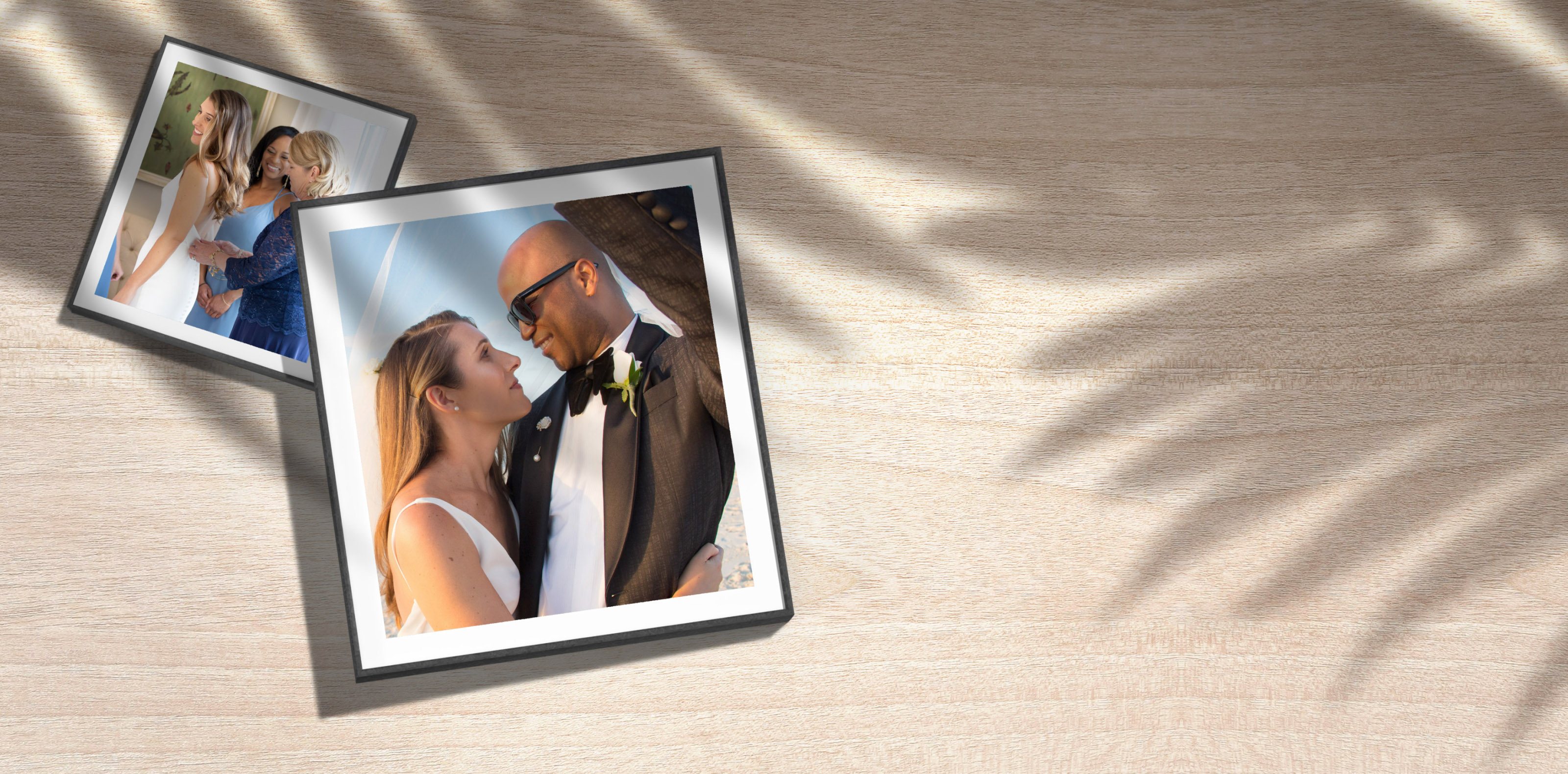 Printed wedding photos on a wooden table under palm shadows