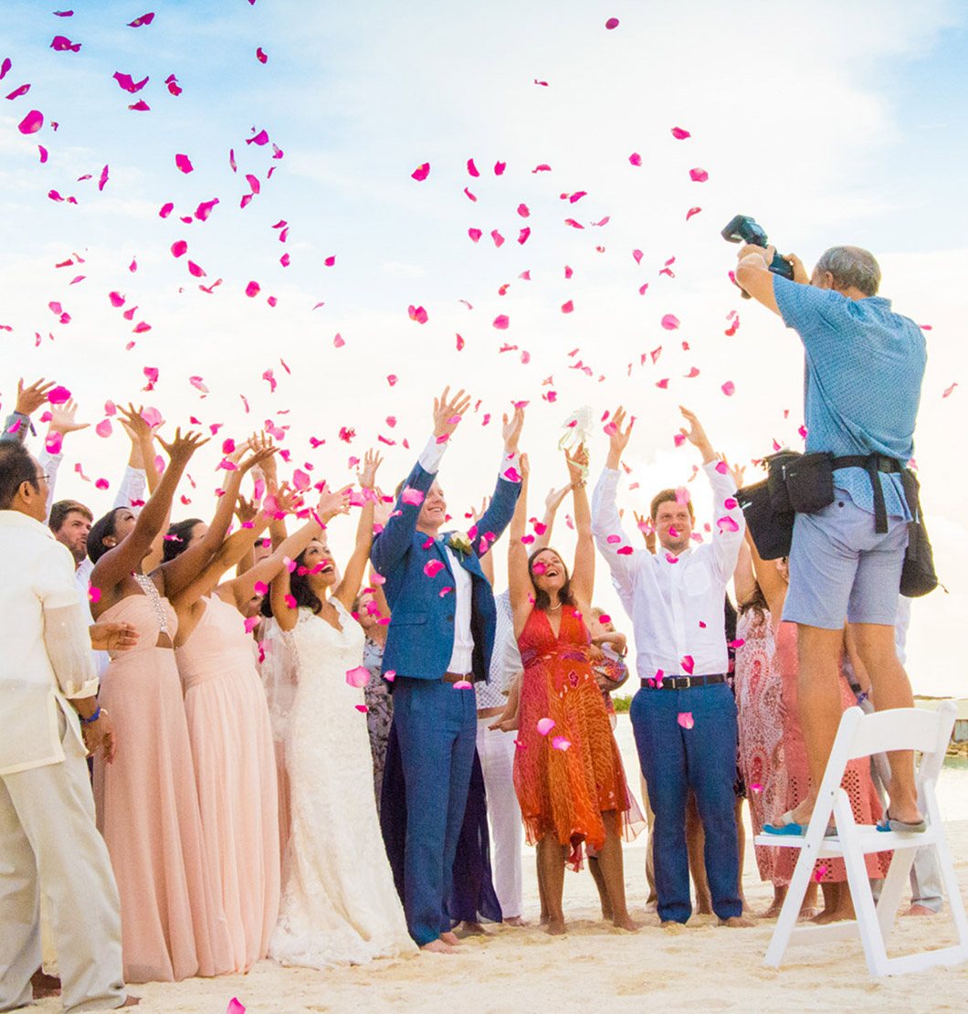 Photographer capturing a flower petal toss at a beach wedding